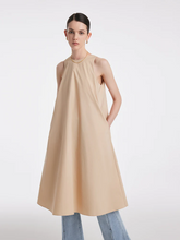 a lady in beige loose a-line vest dress with light blue jeans